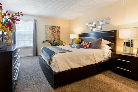 A bedroom with a large bed and a nightstand with a lamp.