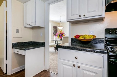 A kitchen with white cabinets and a black countertop.