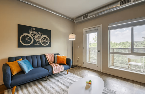 A living room with a blue couch and a motorcycle picture on the wall.
