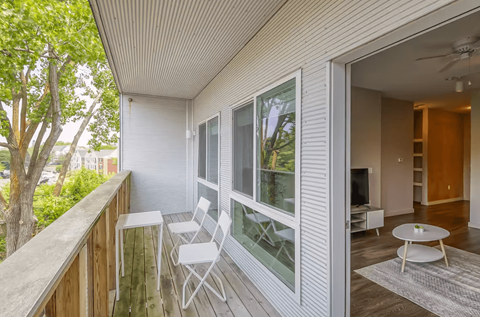 A balcony with a table and chairs overlooking a tree.