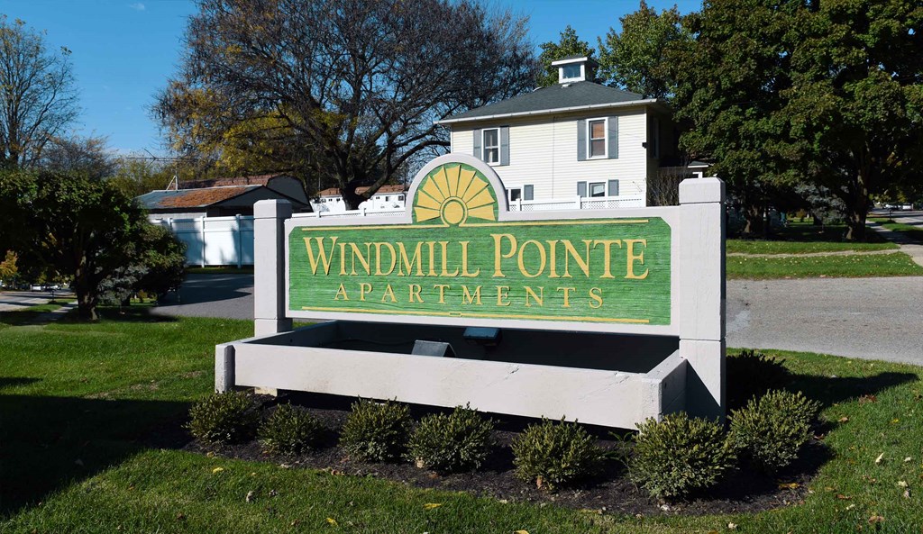 A sign for Windmill Pointe Apartments in front of a building.