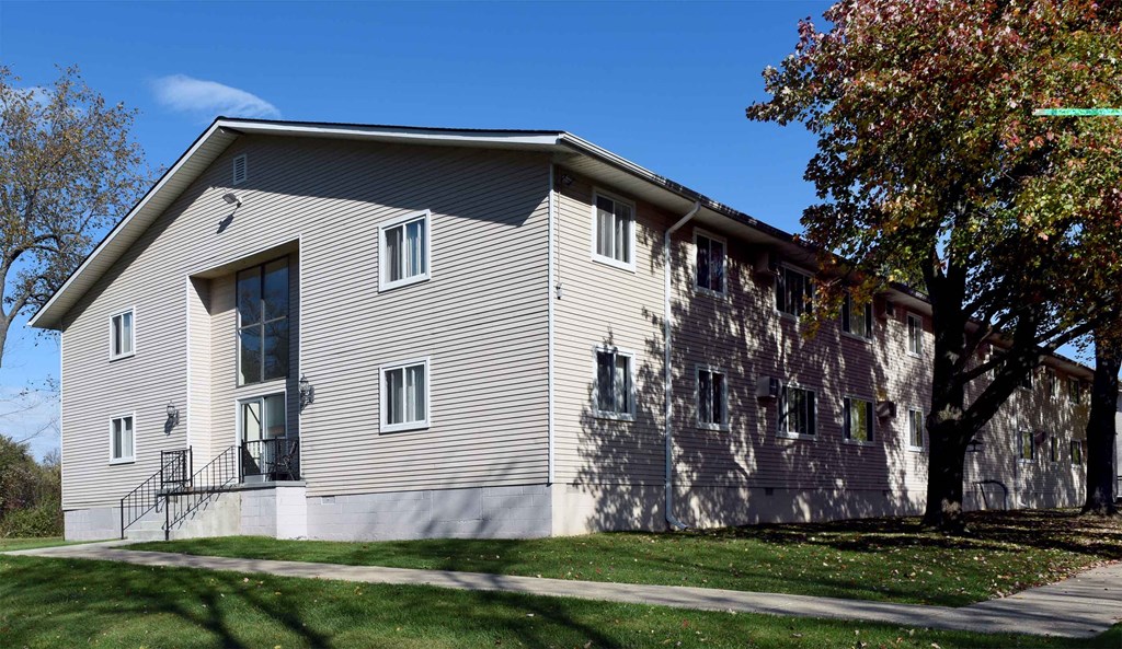 A grey building with a tree in front of it.
