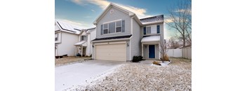 A house with a garage and a driveway covered in snow.