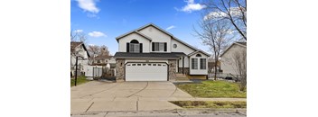 A two-story house with a garage is surrounded by a driveway and a sidewalk.
