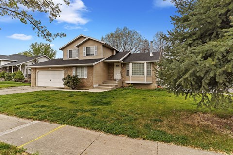 the front of a house with a lawn and trees