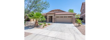 A house with a driveway and palm trees in front.