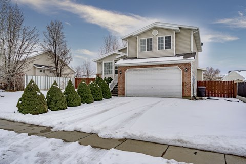 A house with a white garage door and a snow-covered ground.