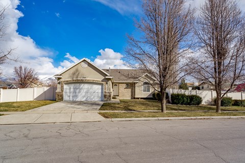 A house with a white garage door is surrounded by a white fence.