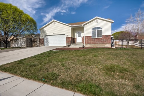 A house with a white garage door and a brown brick wall.