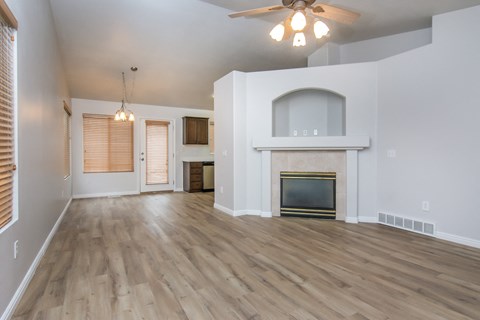 an empty living room with a fireplace and a ceiling fan