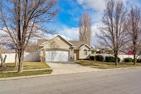 A house with a garage is surrounded by bare trees.