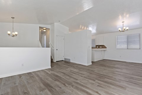 A spacious room with wood flooring and white walls.