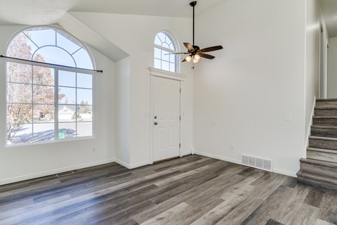 A room with a ceiling fan and a window with a view of a tree.