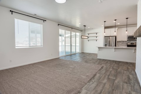 A spacious living room with a sliding glass door leading to a balcony.
