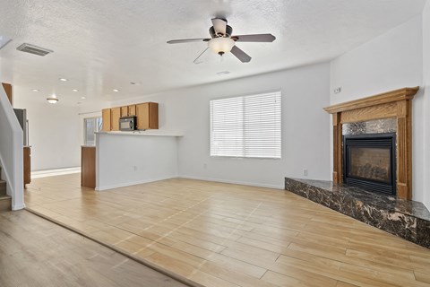 A spacious living room with a fireplace and a ceiling fan.