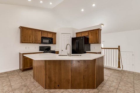 A kitchen with a white counter top and wooden cabinets.