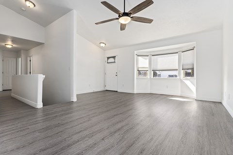 A room with a ceiling fan and a large window.