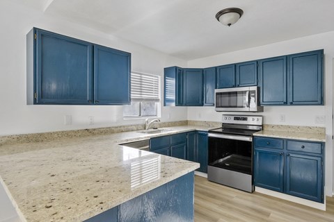 A kitchen with blue cabinets and a granite countertop.