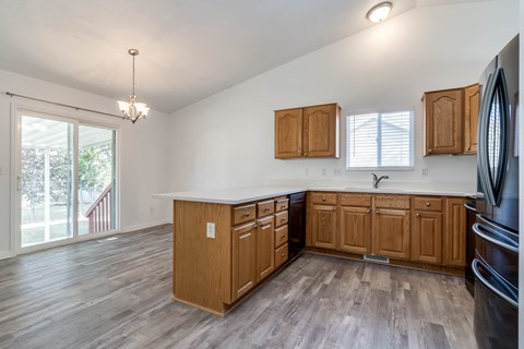 A kitchen with wooden cabinets and a black refrigerator.