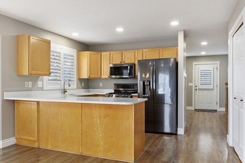 A kitchen with wooden cabinets and a black refrigerator.