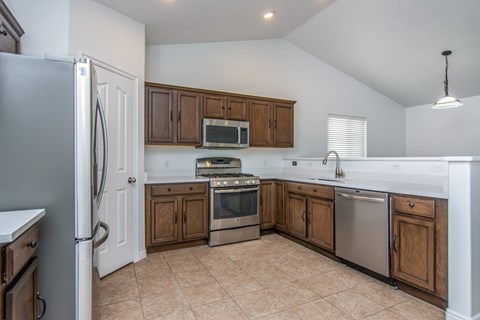 A kitchen with a refrigerator, oven, microwave, and sink.