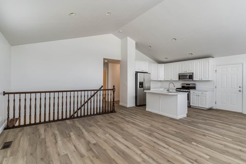 A kitchen with white cabinets and a wooden floor.