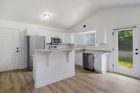 A kitchen with white cabinets and a microwave on the counter.