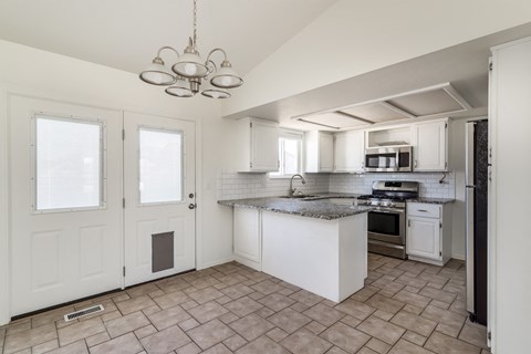 A kitchen with white cabinets and a tile floor.