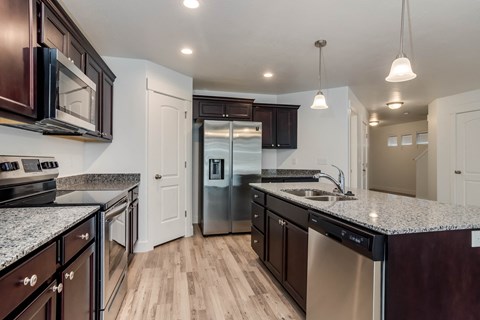 A modern kitchen with dark wood cabinets and stainless steel appliances.