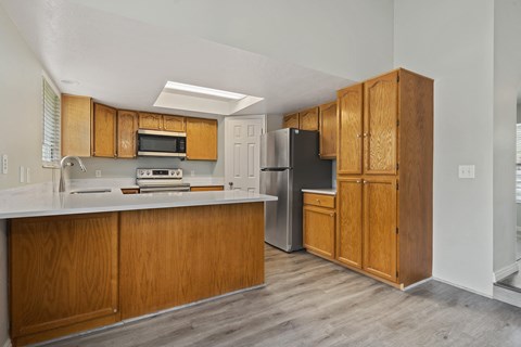 A kitchen with wooden cabinets and a black refrigerator.