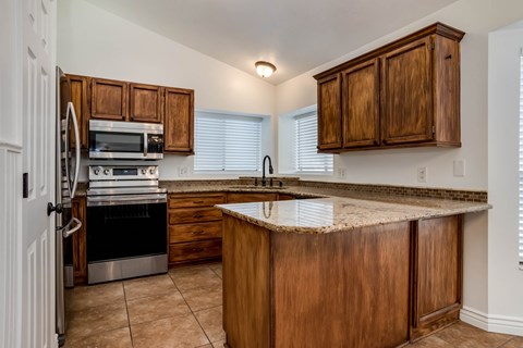 A kitchen with wooden cabinets and a granite countertop.