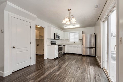 A kitchen with white cabinets and a wooden floor.