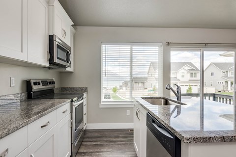 A kitchen with white cabinets and a granite countertop.