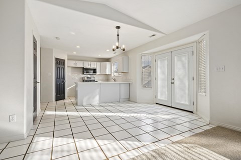 an open kitchen and living room with white cabinets and tiled flooring