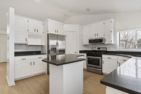 A kitchen with white cabinets and a black countertop.