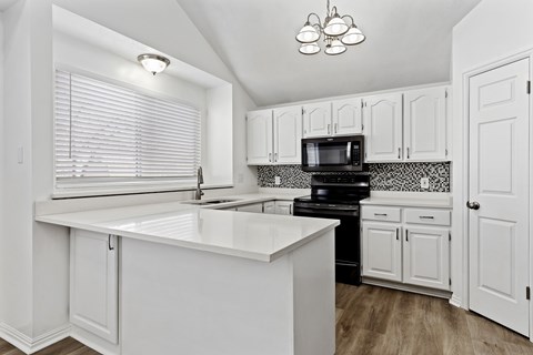 A kitchen with white cabinets and a black stove top oven.