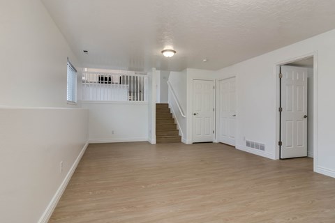 A spacious room with wooden floors and white walls.