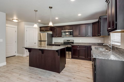 A kitchen with dark brown cabinets and a granite countertop.
