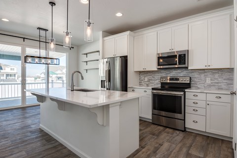 A modern kitchen with white cabinets and a wooden floor.