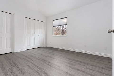 A room with white walls and a window showing trees outside.