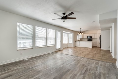 A spacious room with a ceiling fan and wooden flooring.