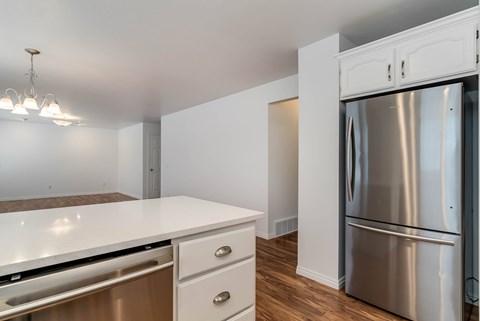 A modern kitchen with a stainless steel refrigerator and white countertops.