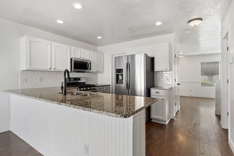 A kitchen with white cabinets and a granite countertop.
