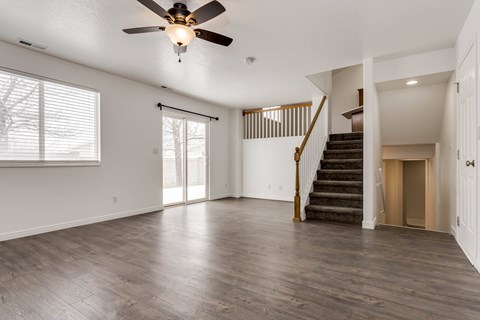 A spacious room with a ceiling fan and wooden flooring.