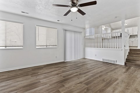 A spacious room with a ceiling fan and wooden flooring.