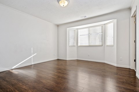 an empty living room with wood floors and a window
