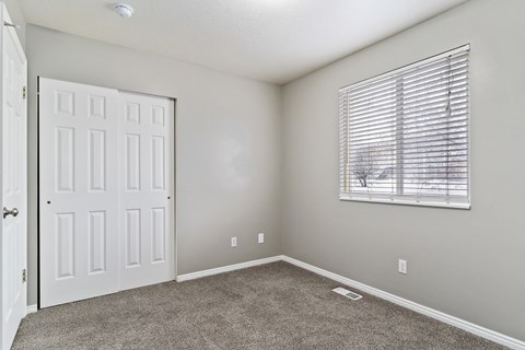 A room with a white door and a window with blinds.