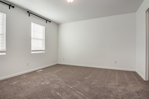A room with a carpeted floor and a window with blinds.