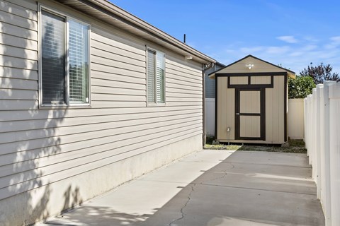 A small building with a brown door is situated next to a house.