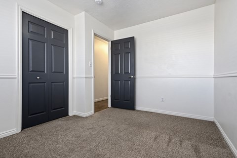 an empty room with black doors and white walls